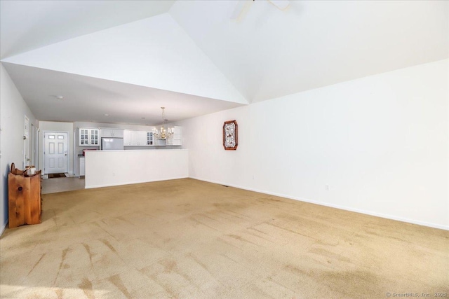 unfurnished living room featuring light colored carpet, lofted ceiling, and a notable chandelier