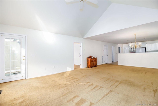 unfurnished living room featuring plenty of natural light, high vaulted ceiling, light colored carpet, and ceiling fan with notable chandelier