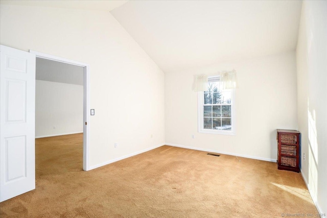 carpeted spare room featuring vaulted ceiling