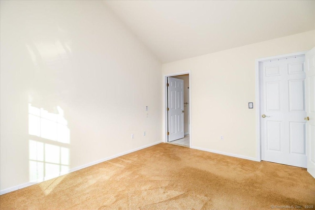 carpeted empty room featuring lofted ceiling