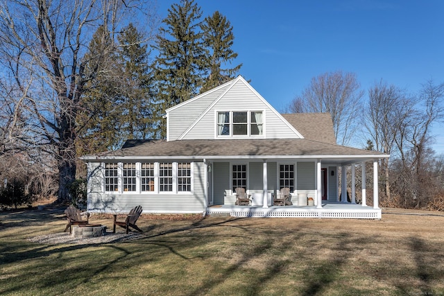 rear view of house featuring a lawn, a porch, and an outdoor fire pit