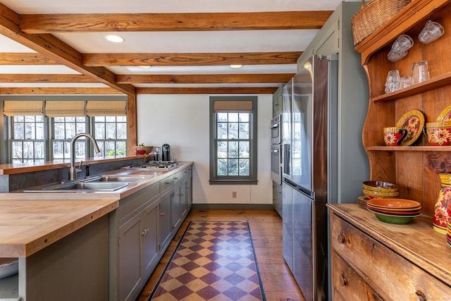 kitchen with beamed ceiling, a healthy amount of sunlight, and sink