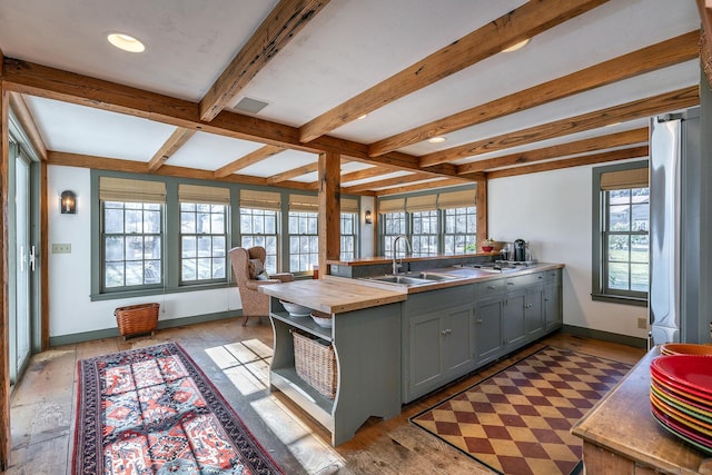 kitchen featuring butcher block counters, gray cabinetry, sink, light hardwood / wood-style flooring, and beamed ceiling