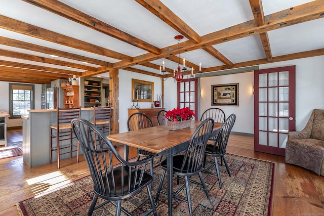 dining room with hardwood / wood-style floors, beam ceiling, an inviting chandelier, and french doors