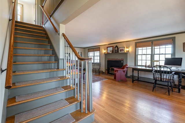 staircase featuring hardwood / wood-style floors, ornamental molding, and a healthy amount of sunlight