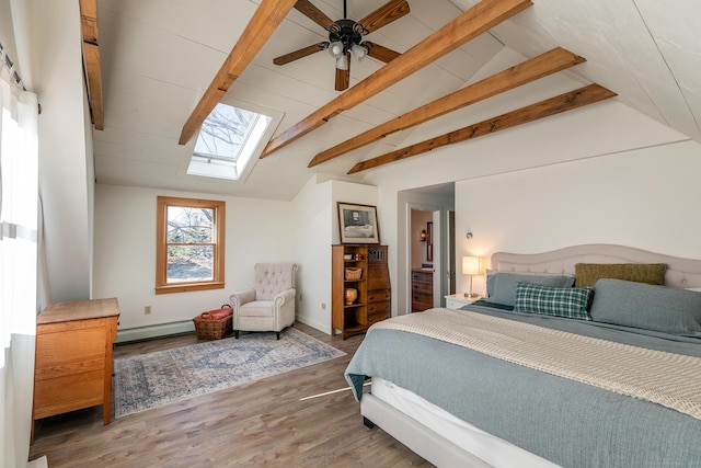 bedroom featuring baseboard heating, ceiling fan, vaulted ceiling with skylight, and hardwood / wood-style flooring