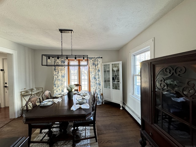 dining area with dark hardwood / wood-style flooring, a baseboard radiator, and a textured ceiling