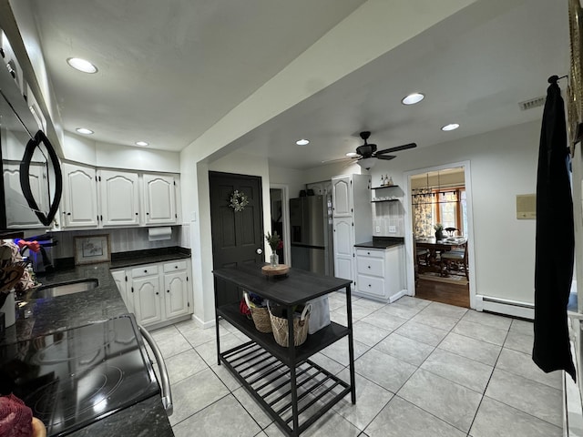 kitchen with white cabinets, stainless steel fridge, a baseboard heating unit, light tile patterned floors, and electric stove