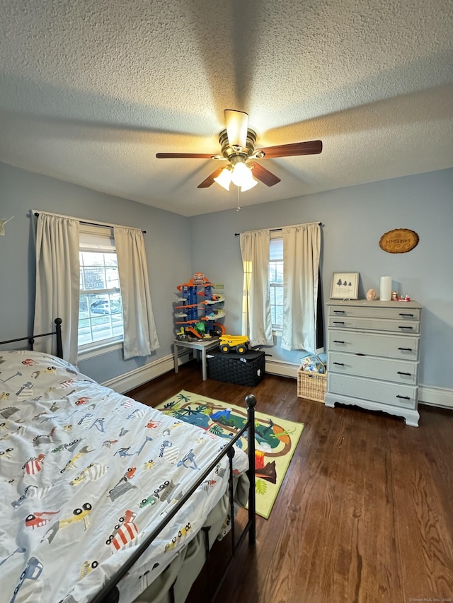 bedroom with dark wood-type flooring, a baseboard radiator, ceiling fan, and a textured ceiling