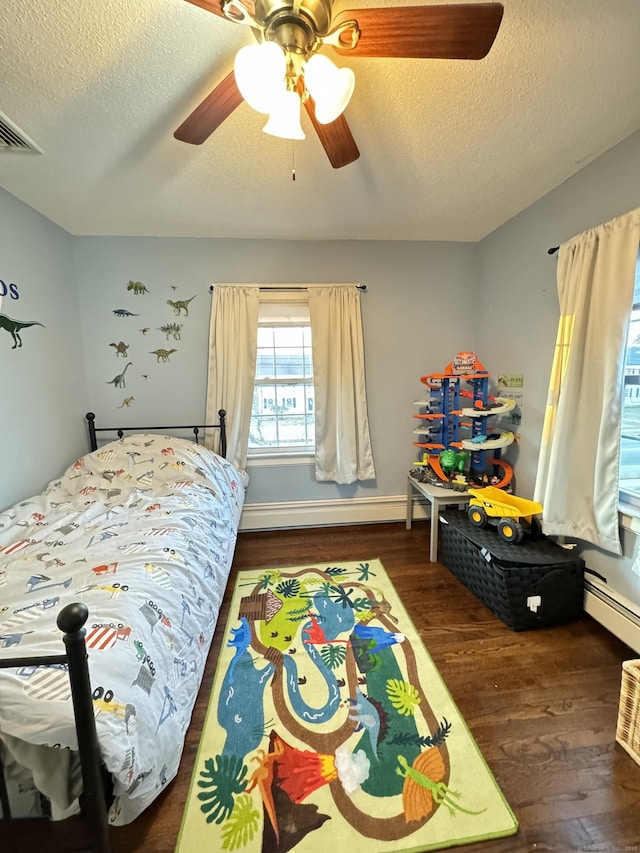 bedroom with ceiling fan, a baseboard radiator, dark hardwood / wood-style flooring, and a textured ceiling