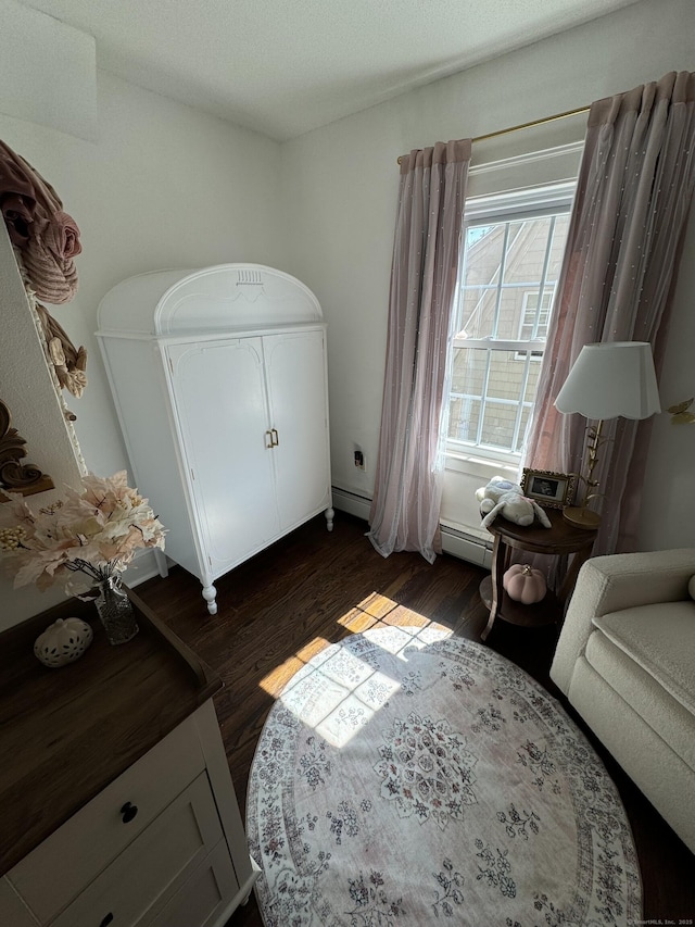 bedroom with a baseboard heating unit and dark wood-type flooring