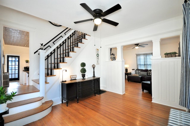 stairway with hardwood / wood-style flooring, ceiling fan, ornamental molding, and decorative columns