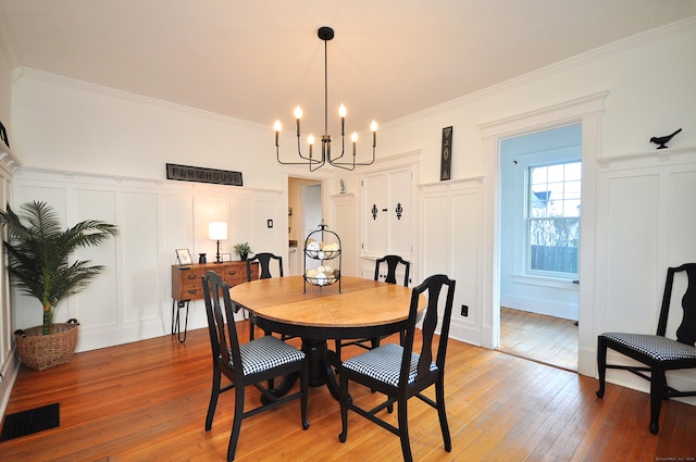 dining area featuring an inviting chandelier, hardwood / wood-style floors, and ornamental molding