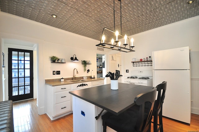 kitchen with a kitchen island, sink, white cabinets, a kitchen bar, and white appliances