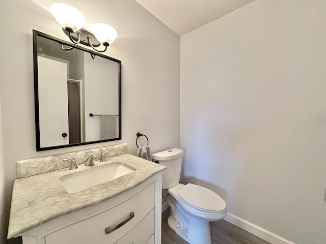 bathroom featuring wood-type flooring, vanity, toilet, and vaulted ceiling