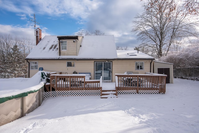 snow covered rear of property with an outdoor structure and a deck