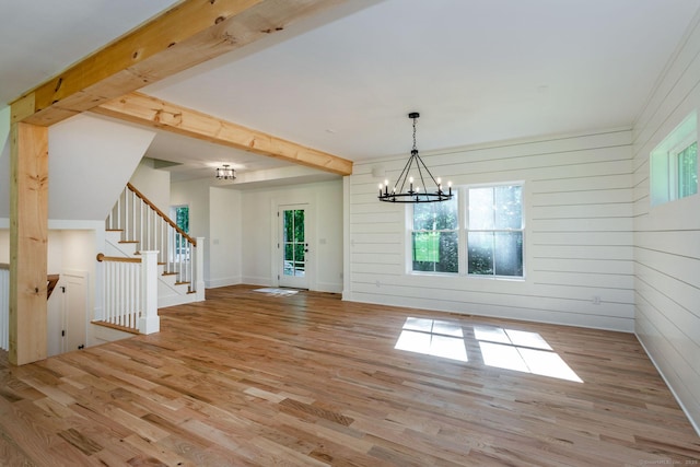 unfurnished dining area featuring beamed ceiling, a notable chandelier, and light wood-type flooring