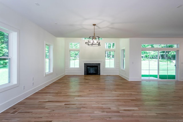 unfurnished living room with a notable chandelier and light hardwood / wood-style floors