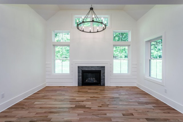 unfurnished living room featuring high vaulted ceiling, a chandelier, and light hardwood / wood-style flooring