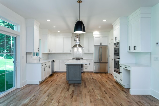 kitchen with sink, white cabinetry, decorative light fixtures, a center island, and stainless steel appliances