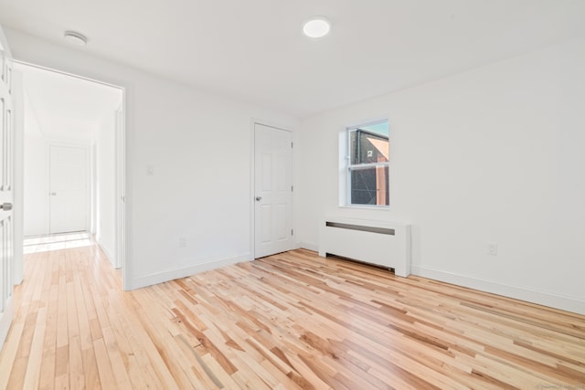 unfurnished room with light wood-type flooring and radiator