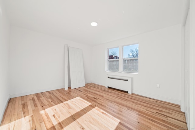 spare room with radiator heating unit and light hardwood / wood-style flooring