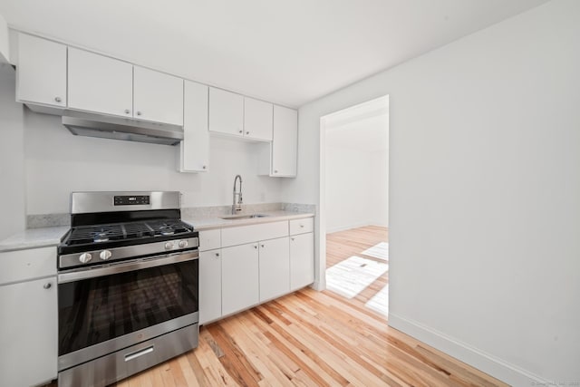 kitchen featuring white cabinets, light hardwood / wood-style floors, stainless steel gas range oven, and sink