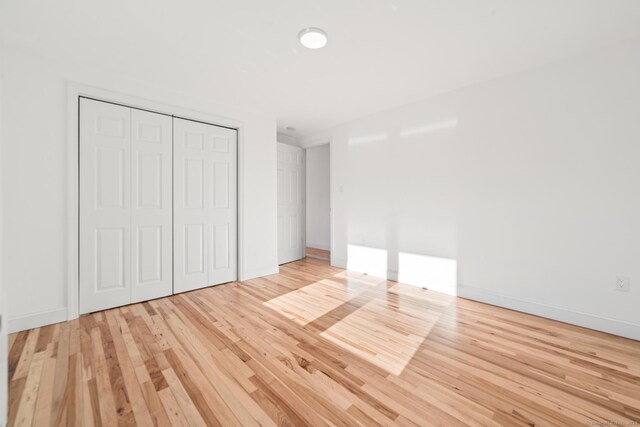 unfurnished bedroom featuring light hardwood / wood-style flooring and a closet