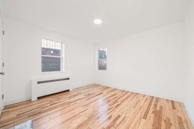 spare room featuring light wood-type flooring and radiator