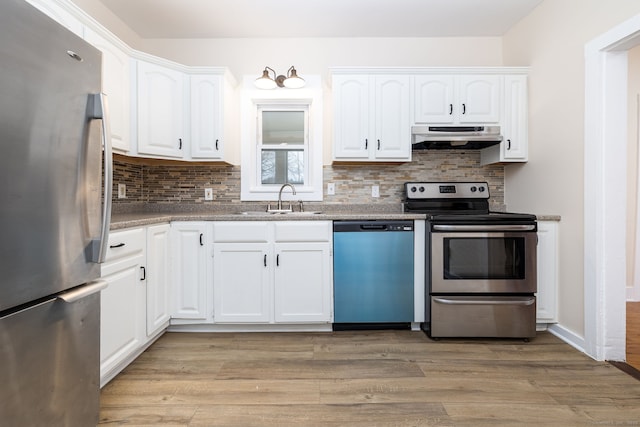 kitchen with white cabinetry, light hardwood / wood-style floors, appliances with stainless steel finishes, decorative backsplash, and sink