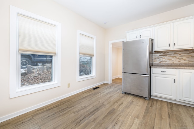 kitchen with tasteful backsplash, white cabinets, stainless steel fridge, and light hardwood / wood-style floors