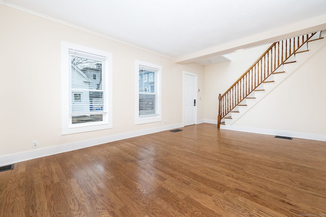 unfurnished living room featuring hardwood / wood-style flooring and crown molding