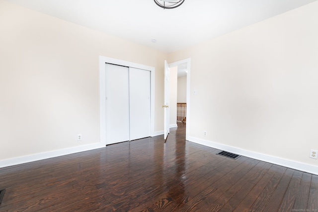 unfurnished bedroom with dark wood-type flooring and a closet