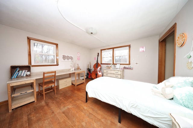 bedroom with hardwood / wood-style flooring, built in desk, and a baseboard radiator