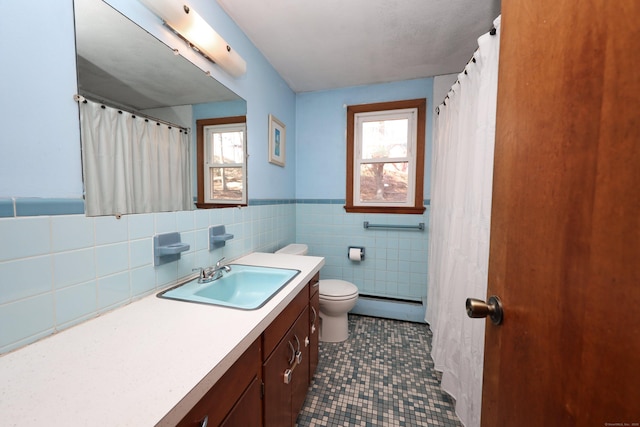 bathroom featuring a wealth of natural light, vanity, toilet, and baseboard heating