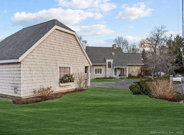 rear view of property with a lawn and roof with shingles