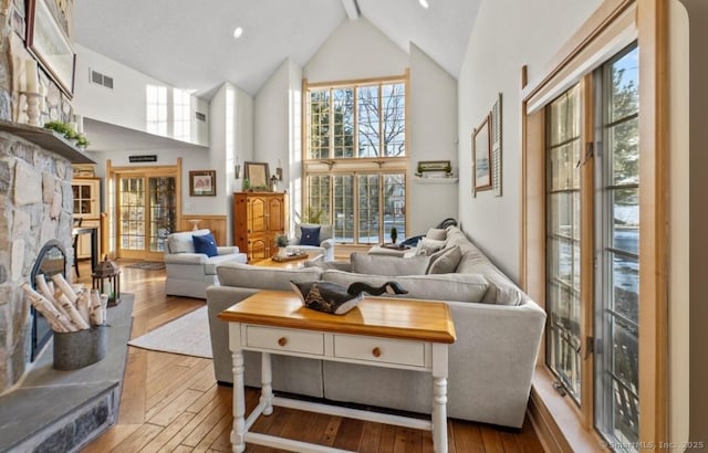 living room with high vaulted ceiling, wood-type flooring, a fireplace, and visible vents