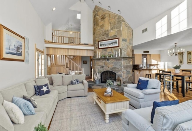 living room with a fireplace, wood finished floors, visible vents, stairway, and an inviting chandelier