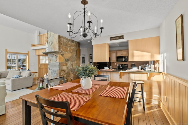 dining area featuring light wood-style floors, a fireplace, and an inviting chandelier