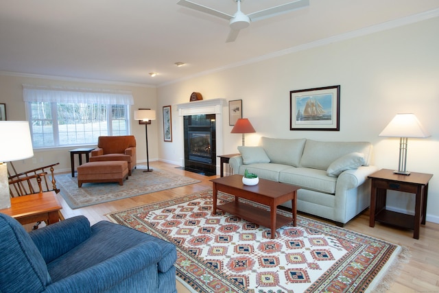 living room featuring ceiling fan, a fireplace, crown molding, and light hardwood / wood-style floors