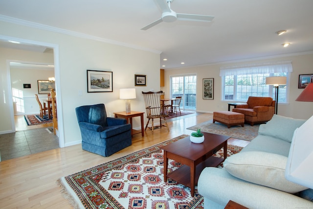 living room with crown molding, light hardwood / wood-style flooring, and ceiling fan with notable chandelier