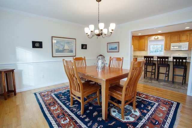 dining area featuring a chandelier, light wood-type flooring, and ornamental molding