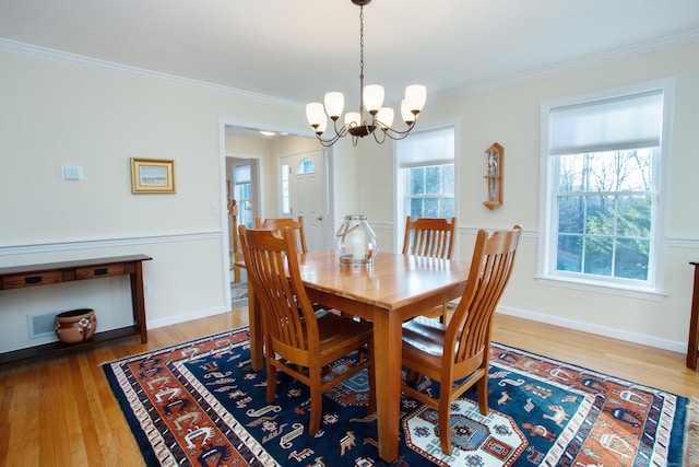 dining area featuring wood-type flooring, crown molding, and a chandelier