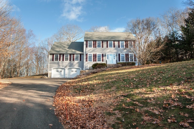 colonial house featuring a front lawn and a garage