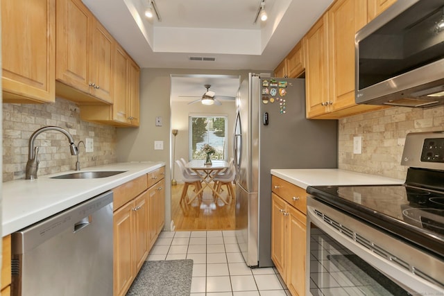 kitchen featuring sink, ceiling fan, appliances with stainless steel finishes, a tray ceiling, and light tile patterned flooring