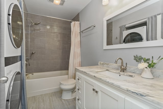 full bathroom featuring stacked washer and dryer, toilet, shower / tub combo, vanity, and hardwood / wood-style flooring