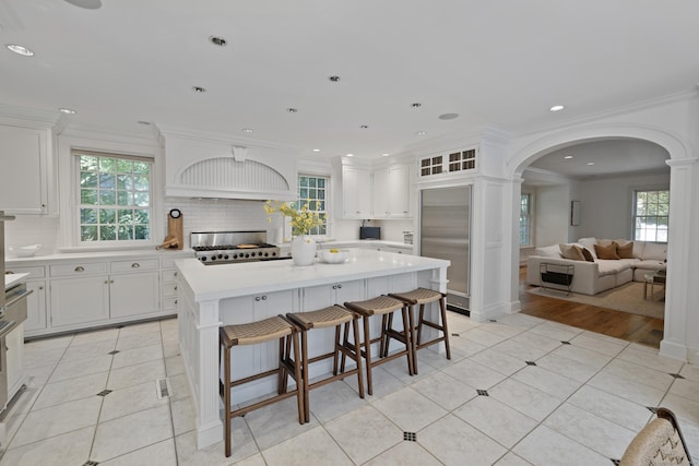 kitchen featuring a center island, white cabinets, ornamental molding, tasteful backsplash, and a kitchen bar