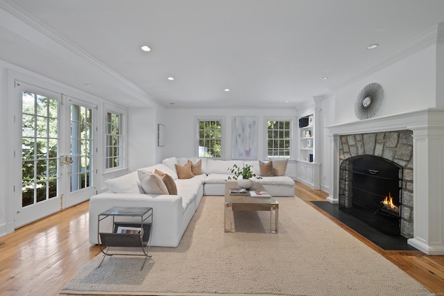 living room featuring hardwood / wood-style floors, built in shelves, ornamental molding, and a fireplace