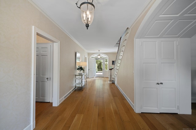 corridor featuring hardwood / wood-style flooring, a notable chandelier, and crown molding