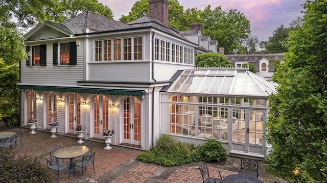 back house at dusk featuring a patio